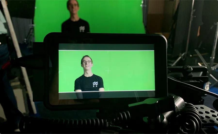 Man with Duffel tee-shirt in front of green screen being recorded by professional camera.